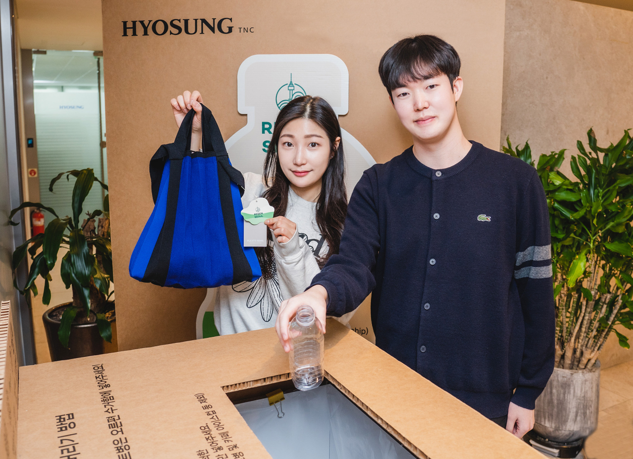 효성티앤씨 직원들이 페트병 수거함 앞에서 리젠 적용 가방과 재활용할 페트병을 들고 있다. [효성 제공]