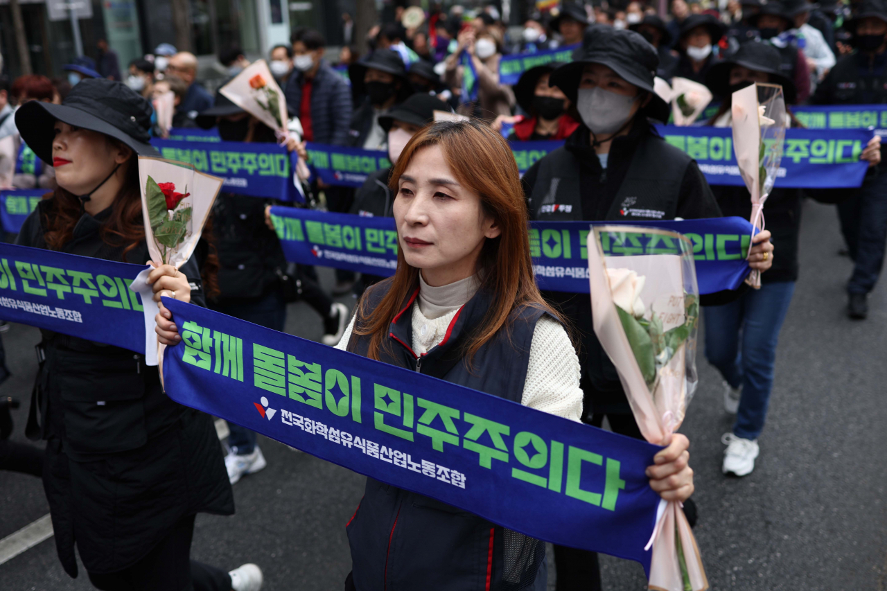 Female union members took to the streets in central Seoul on Wednesday to mark International Women's Day, carrying signs saying "Caring together is democracy." (Yonhap)
