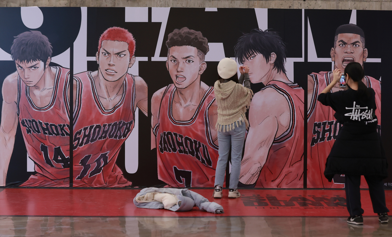 In this photo taken on Feb. 16, visitors to a Seoul theater take a photo of the poster of the Japanese animated film "The First Slam Dunk." (Yonhap)