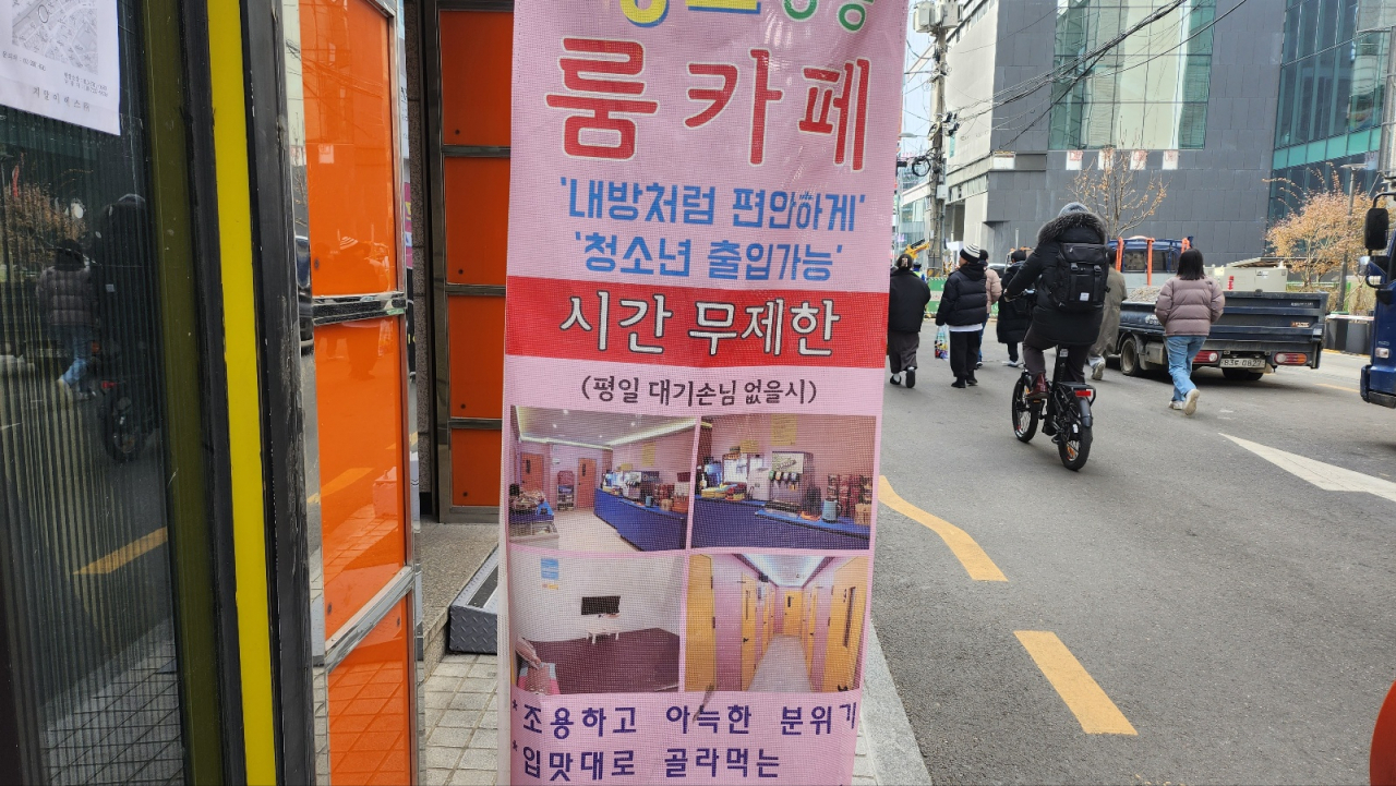 Pedestrians walk by a banner advertising a room cafe in Mapo-gu, Seoul, which mentions "Adolescents are allowed." (Lee Jung-youn/The Korea Herald)
