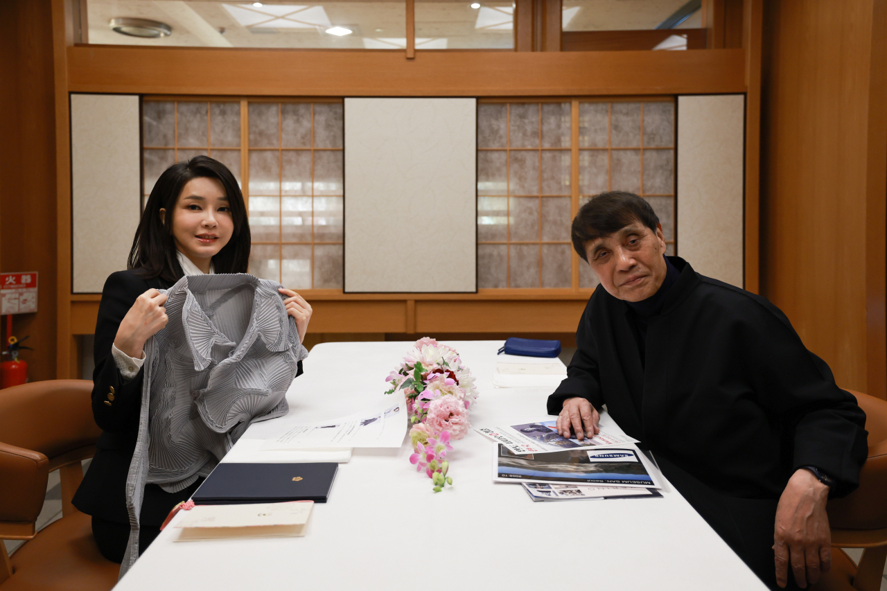 김건희 여사가 17일 일본 도쿄 한 식당에서 세계적인 건축가 안도 다다오와 오찬을 하며 이세이미야케 옷을 선물받고 있다. [연합]