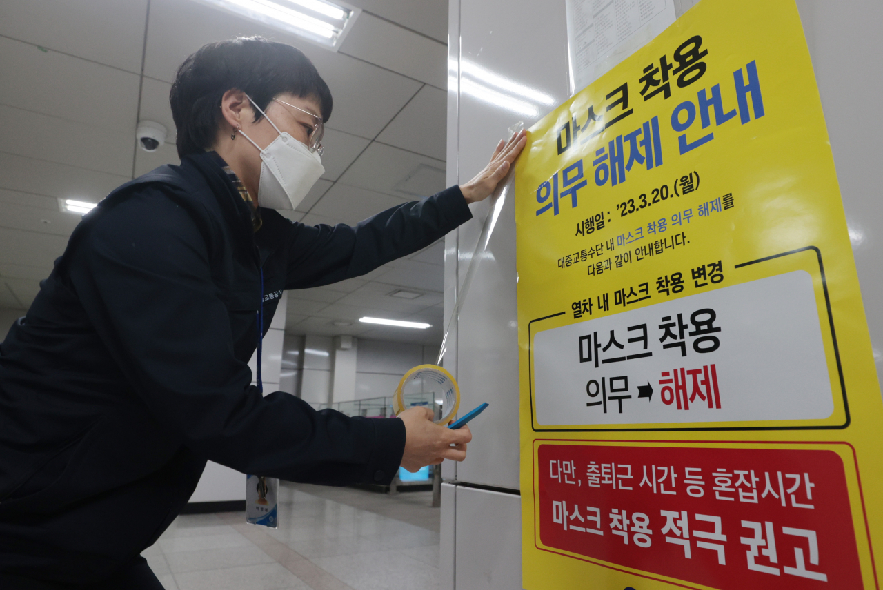 20일부터 대중교통 마스크 착용 의무가 해제된다. 중앙방역대책본부는 실내 마스크 의무 해제 이후 한 달 반이 지난 시점에서도 코로나19 유행이 감소세가 지속되고, 자율적인 마스크 착용이 이뤄지고 있는 점을 고려해 버스·지하철, 택시 등 대중교통에서의 마스크 착용 의무도 풀기로 했다. 사진은 19일 서울 지하철역에서 관계자가 안내문을 붙이고 있는 모습. [연합]