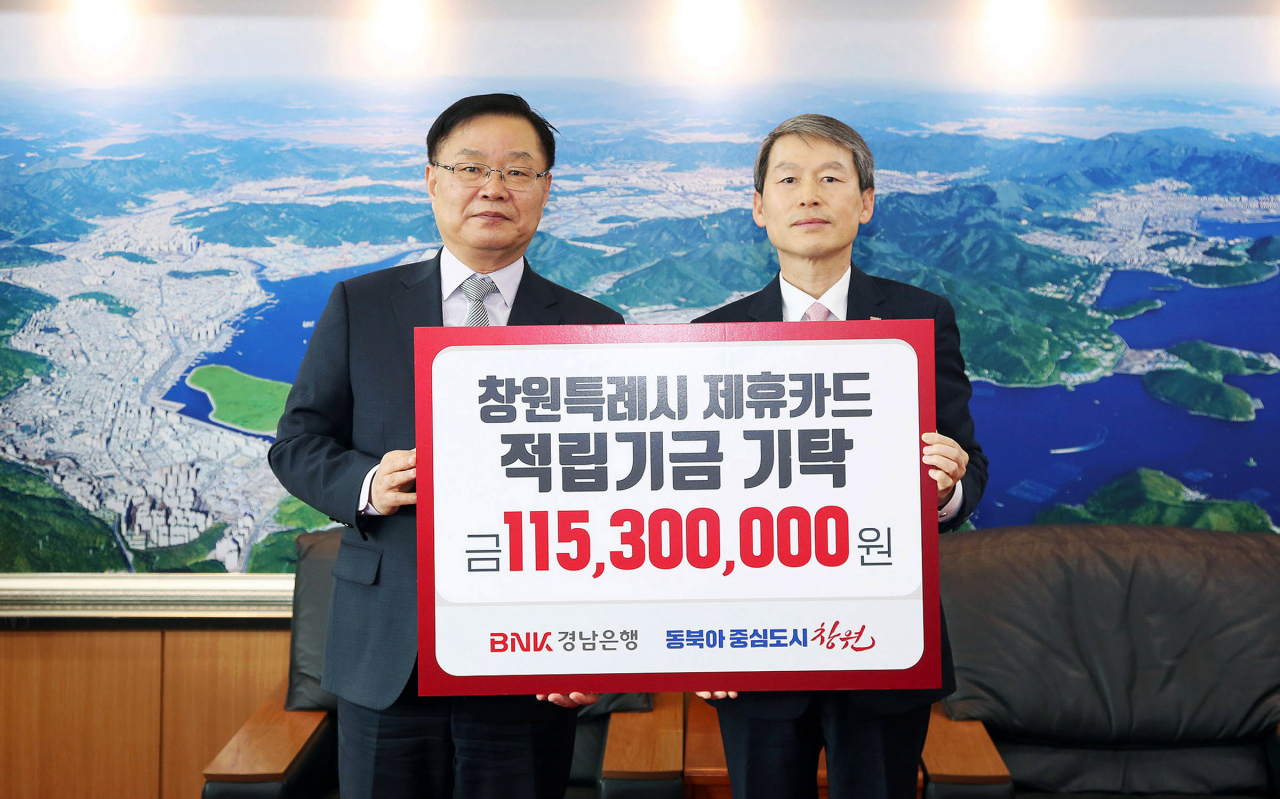 BNK경남은행 김영원 그룹장(사진 오른쪽)이 창원특례시 홍남표 시장에게 ‘제휴카드 적립기금 기탁 증서’를 전달하고 있다. [BNK경남은행 제공]