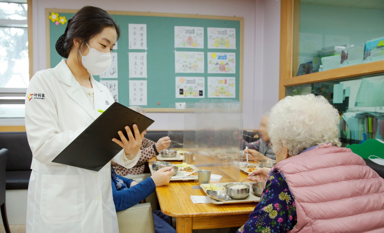 아워홈 소속 영양사가 서울 마포구에 위치한 한서데이케어센터에서 ‘인지기능개선 관리 식단’을 시설 이용 어르신에게 소개하고 있다. [아워홈 제공]