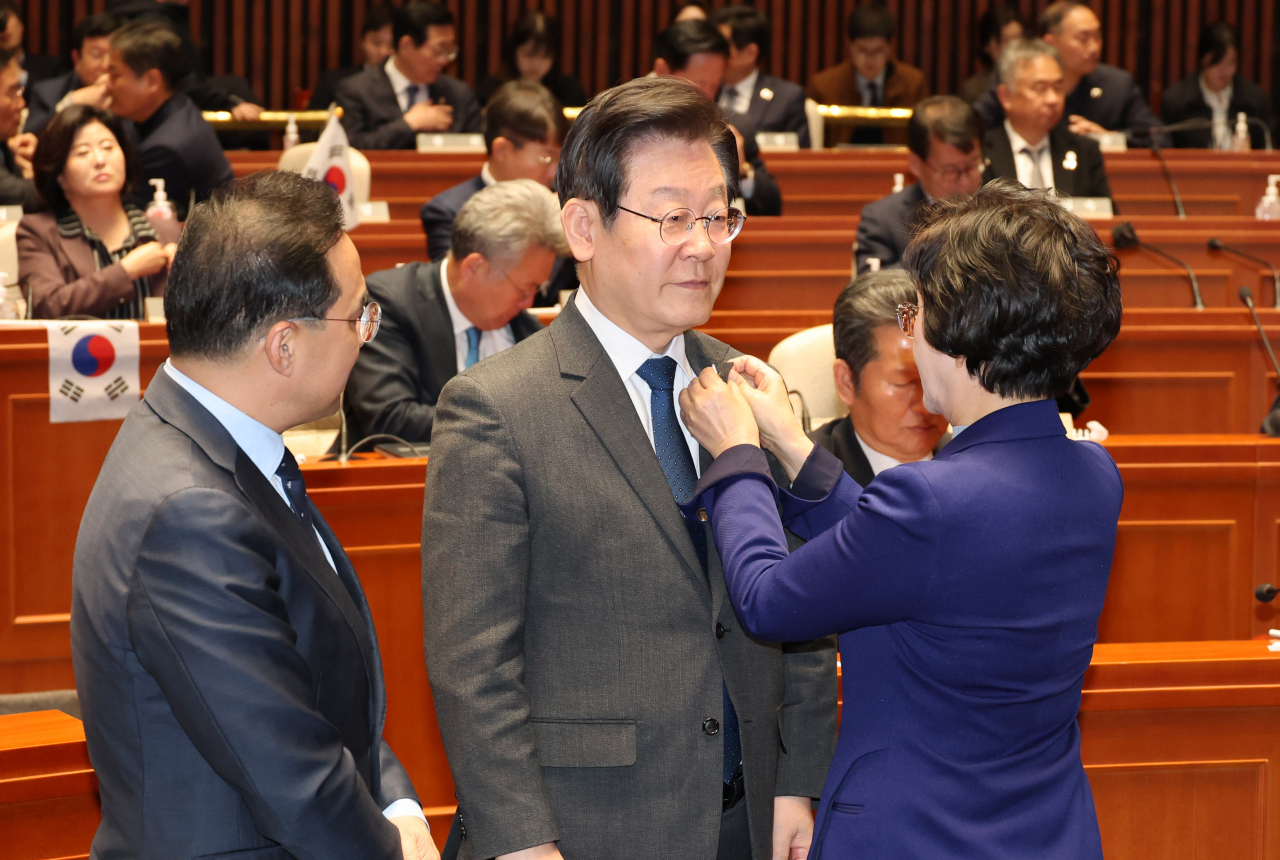 김상희 더불어민주당 대일굴욕외교대책위원장이 16일 오후 서울 여의도 국회에서 열린 의원총회에서 이재명 대표에게 태극기 배지를 달아주고 있다. [연합]