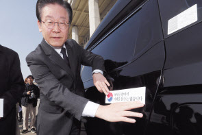 이재명 더불어민주당 대표가 22일 국회 본청 앞에서 당 행사인 ‘대일굴종외교 규탄 태극기달기 운동’ 일환으로 자신의 차량에 태극기 스티커를 붙이고 있다. 임세준 기자