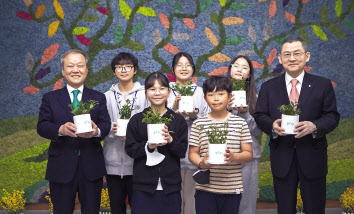 김신연(오른쪽) 한화사회봉사단 사장과 최열(왼쪽) 환경재단 이사장이 충북 청주 수성초 학생들과 함께 벽면에 조성된 모스월 앞에서 공기정화 식물을 들고 있다. [한화 제공]
