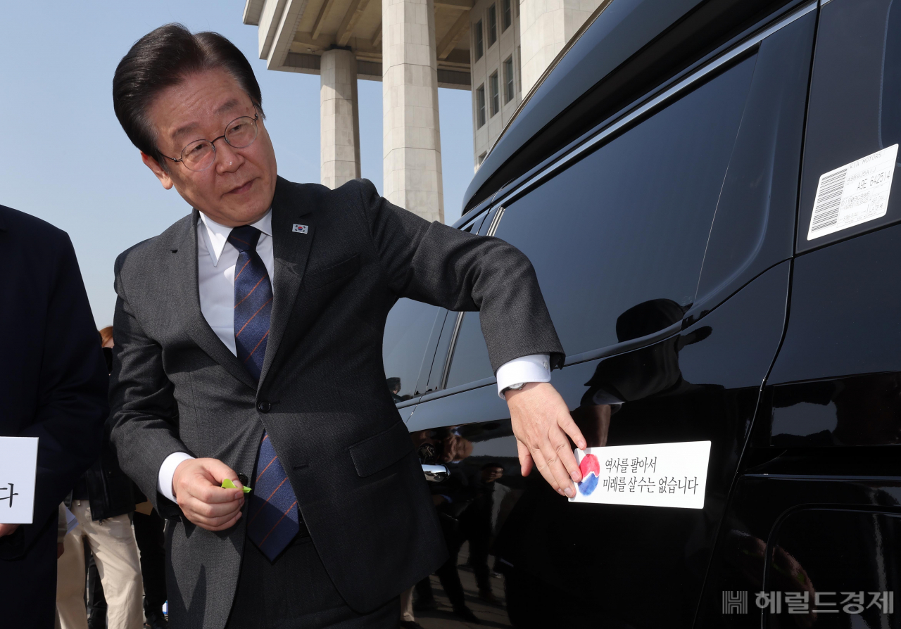 더불어민주당 대일굴종외교 규탄 태극기달기 운동 행사가 22일 서울 영등포구 여의도 국회 본청 앞에서 열려 이재명 대표가 '역사를 팔아서 미래를 살 수는 없습니다' 문구가 담긴 태극기 스티커를 차량에 붙이고 있다. 임세준 기자