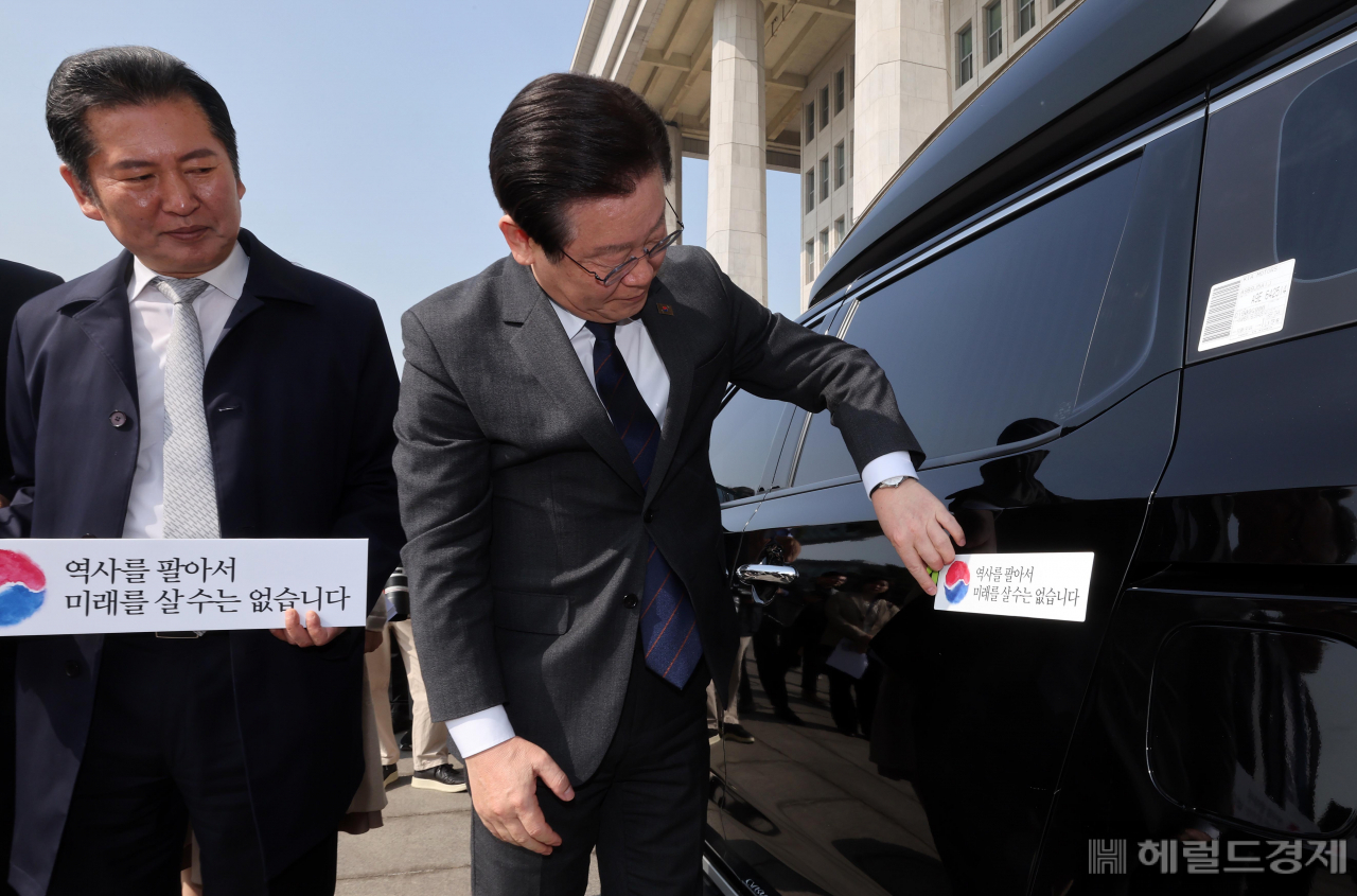 더불어민주당 대일굴종외교 규탄 태극기달기 운동 행사가 22일 서울 영등포구 여의도 국회 본청 앞에서 열려 이재명 대표가 '역사를 팔아서 미래를 살 수는 없습니다' 문구가 담긴 태극기 스티커를 차량에 붙이고 있다. 임세준 기자