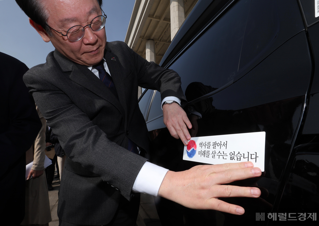 더불어민주당 대일굴종외교 규탄 태극기달기 운동 행사가 22일 서울 영등포구 여의도 국회 본청 앞에서 열려 이재명 대표가 '역사를 팔아서 미래를 살 수는 없습니다' 문구가 담긴 태극기 스티커를 차량에 붙이고 있다. 임세준 기자