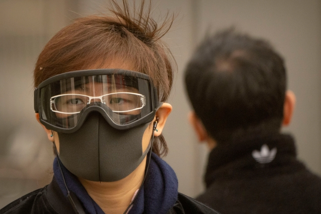 22일 중국 베이징 거리에서 한 시민이 마스크와 고글을 착용한 채 걷고 있다.[AP 연합]