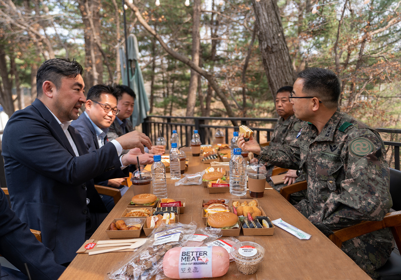 22일 경기 동두천 육군 제28보병사단에서 신세계푸드가 MZ세대 장병을 격려하기 위해 대안육 ‘베러미트(Better Meat)’로 만든 핫도그와 노브랜드 버거 전용 음료 ‘브랜드 콜라’와 ‘브랜드 사이다’를 각 1만개씩 위문품으로 전달했다. 송현석(왼쪽) 신세계푸드 대표가 박춘식(오른쪽) 28사단장에게 ‘베러미트’로 만든 메뉴를 소개하고 있다.[신세계푸드 제공]