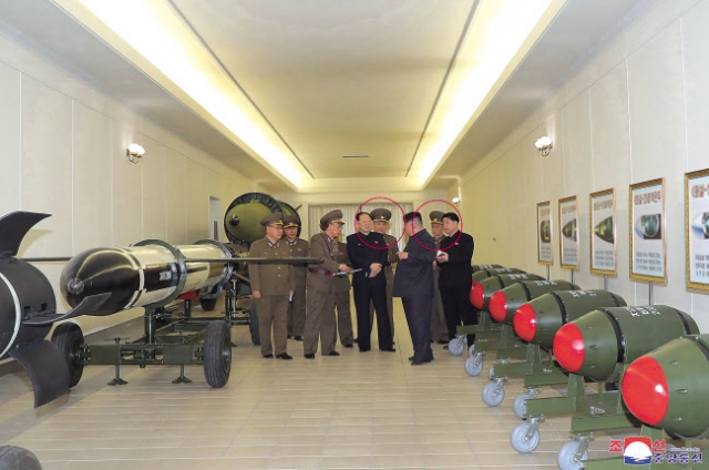 지난 28일 북한이 공개한 ‘화산-31’ 전술핵탄두 앞에서 김정은 북한 국무위원장이 핵무기연구소 관계자들로부터 보고를 받는 모습. 김 위원장 곁에 있는 남성 2명(붉은색 원)의 얼굴은 모자이크 처리돼 핵무기 개발 실무진으로 추정된다. [연합]