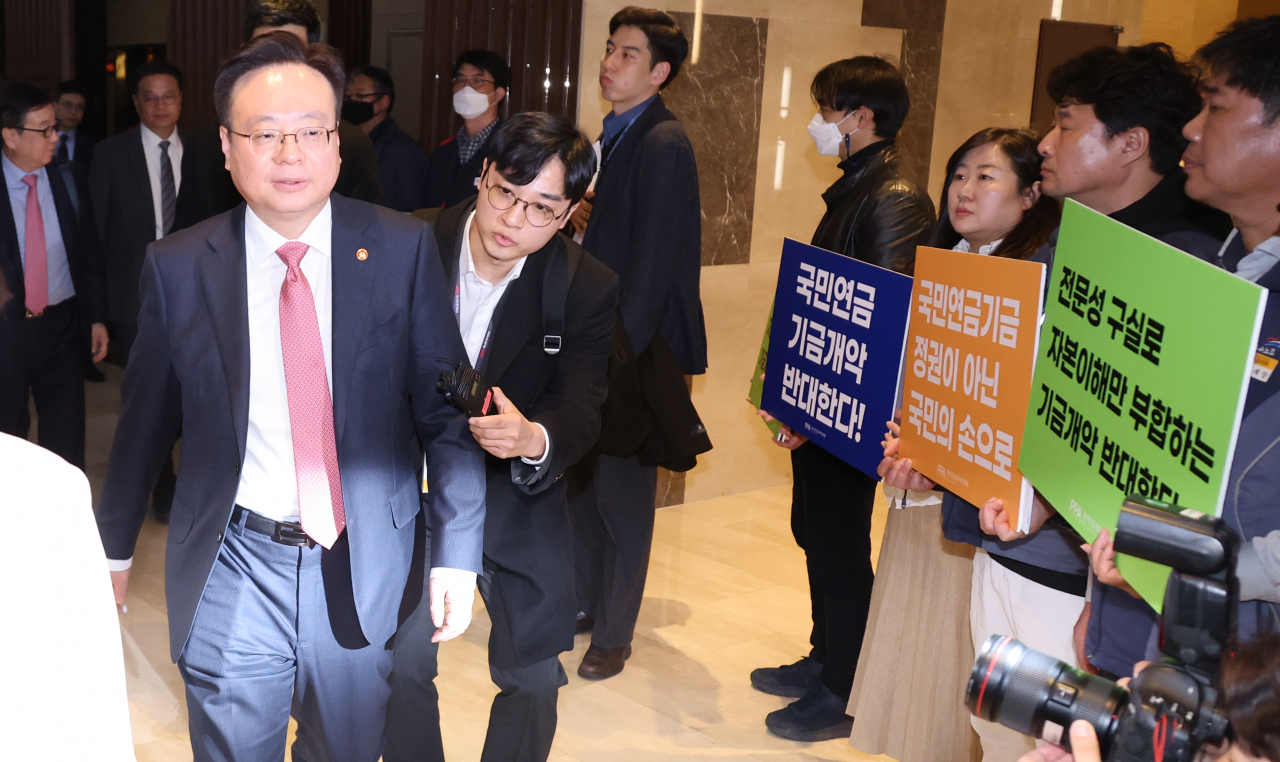 조규홍 보건복지부 장관이 7일 중구 프레지던트 호텔에서 열린 국민연금기금운용위원회에 참석하고 있다. 그 뒤에 기금 개악에 반대하는 공적연금강화국민행동 회원들이 팻말을 들고 있다. [연합]