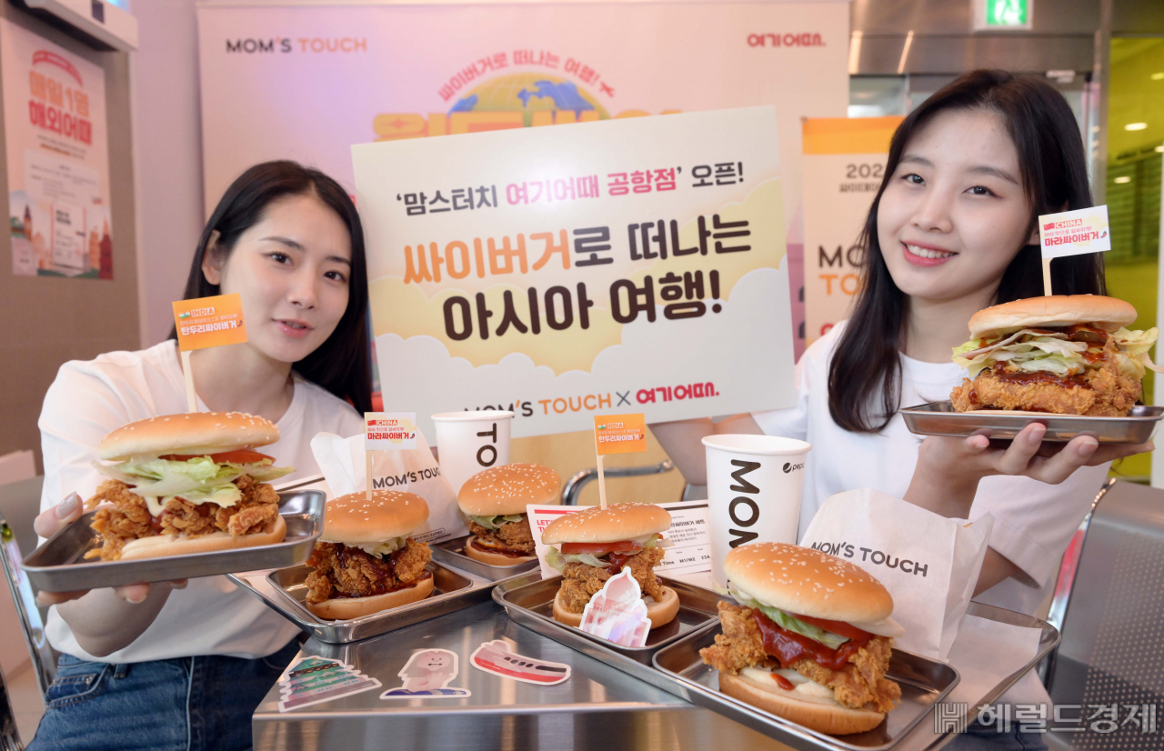 31일 오전 맘스터치가 서울 강남구 맘스터치랩 가든역삼점에서 국내 1위 여행 플랫폼 여기어때와 손잡고 공항 콘셉트의 팝업스토어를 오픈한 가운데 모델들이 4월 2일 ‘싸이데이’를 기념하여 새롭게 출시한 ‘탄두리싸이버거’와 ‘마라싸이버거’를 선보이고 있다. 이상섭 기자