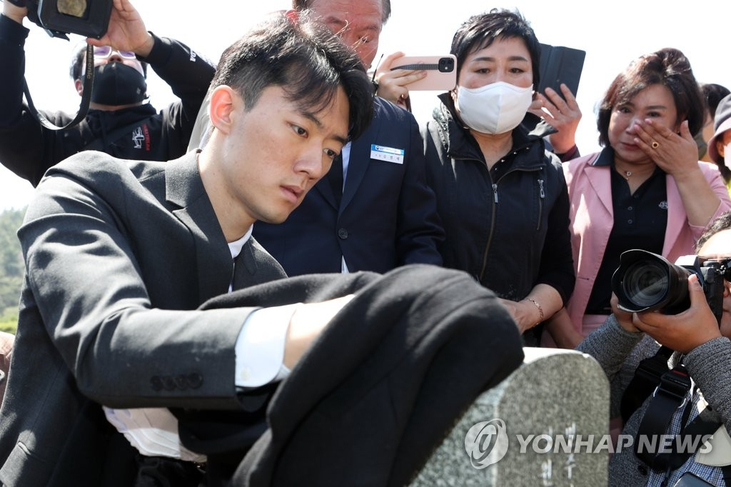 전직 대통령 고(故) 전두환 씨의 손자 전우원 씨가 31일 오전 광주 북구 운정동 국립 5·18민주묘지를 찾아 무명열사 묘비의 먼지를 옷으로 닦고 있다. [연합]