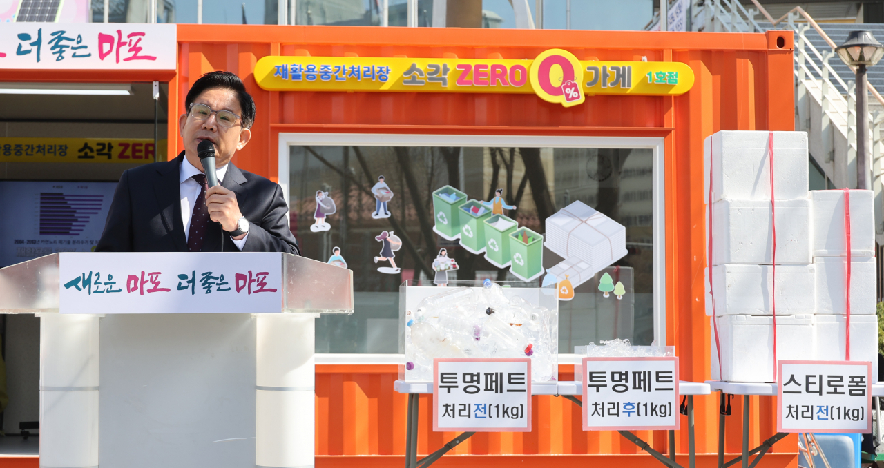 마포구청 소각 제로가게 앞에서 박강수 구청장이 마포형 소각쓰레기 감량 정책을 발표하고 있다. 마포구청 광장에 설치한 소각 제로가게 1호점에는 폐스티로폼을 자원으로 바꾸는 압축기 등이 있다. 재활용품을 무게당 제로페이로 환급한다. 자원순환 도우미가 상주하고 있다. [연합]