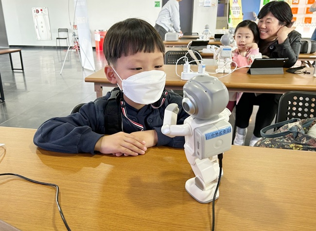 순천만잡월드 어린이 관람객이 호기심 어린 눈빛으로 '순봇'과 이야기를 나누고 있다. [순천시 제공]