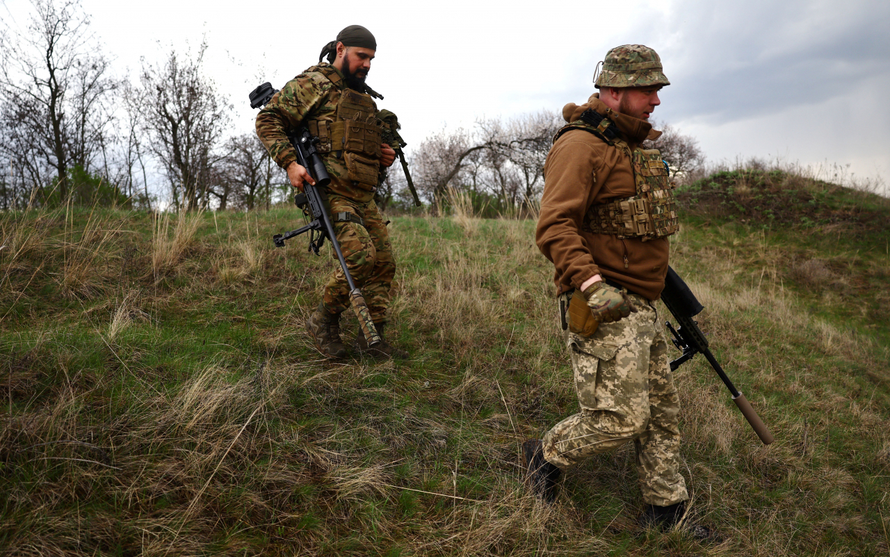 Serhii (35) and Andrii (29), Ukrainian snipers with the 1st Tank Brigade, rush to their vehicle prior to a mission amid Russia's attack on Ukraine at the frontline near Donetsk, Ukraine, on April 8. (Reuter)