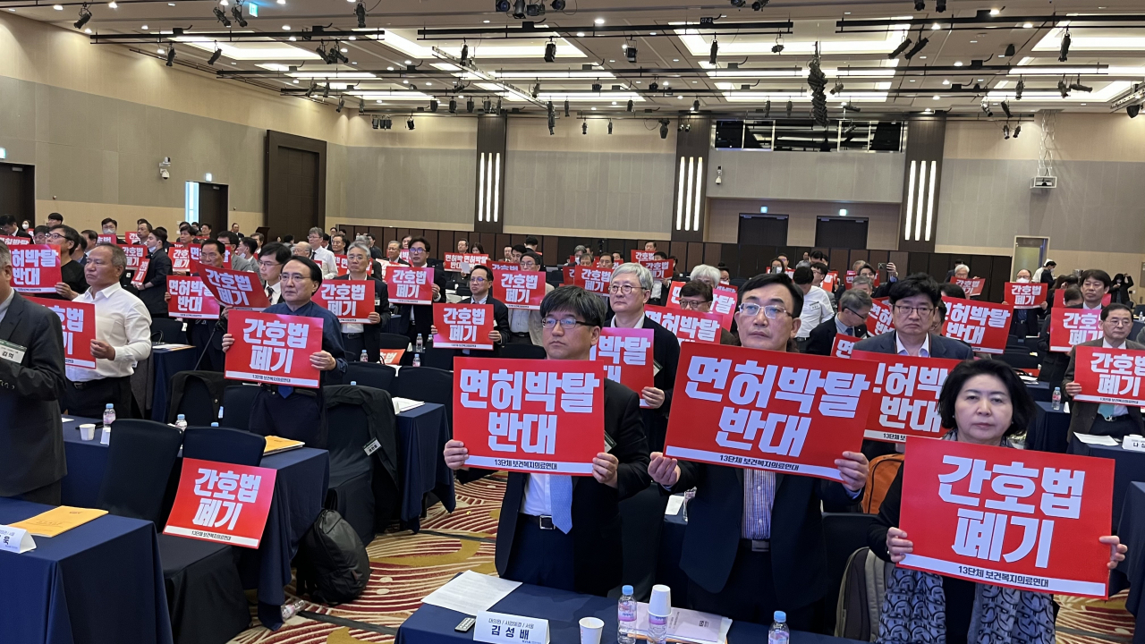 23일 서울 서초구 더케이호텔서울에서 열린 '대한의사협회 제75차 정기대의원총회'에서 참석자들이 간호법과 의료인 면허박탈법 저지를 위한 피켓을 들고 있다. [연합]