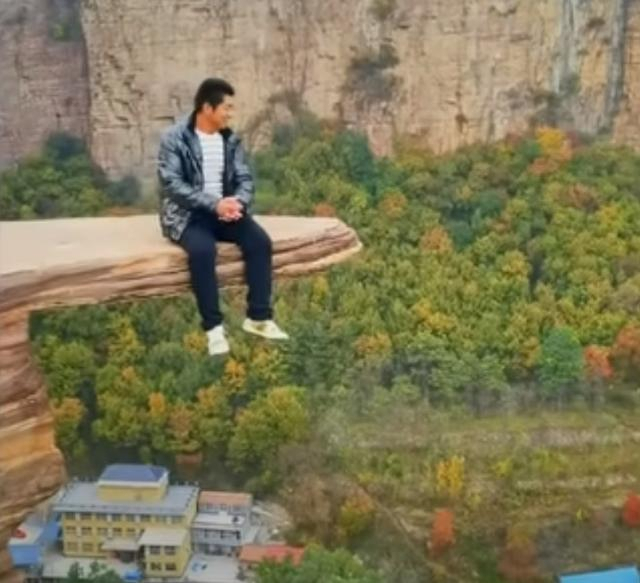 한 중국인 등산객이 허난성 안양시의 협곡에 위치한 이른바 '담대한 바위'에 올라 사진을 찍고 있다. [사우스차이나모닝포스트]