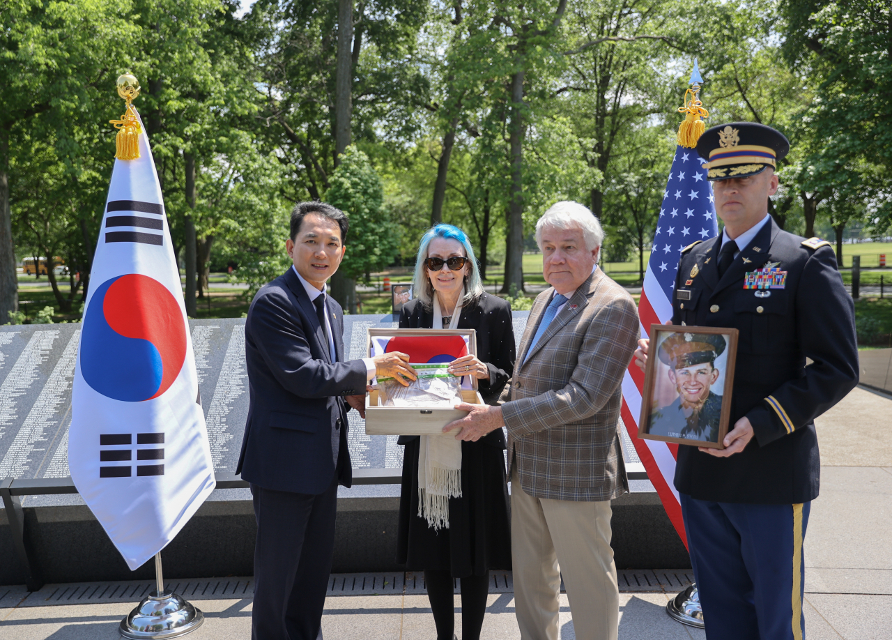 박민식 국가보훈처장이 27일 미국 워싱턴 한국전 전사자 추모의 벽을 방문, 한·미 정상의 '한국전 전사자 신원확인 공동성명' 채택 계기를 마련한 고(故) 루터 스토리 상병을 추모하며 유족에게 스토리 상병의 유해 발굴 지역인 경남 창녕의 흙과 AI 복원 액자 전달하고 있다. [연합]