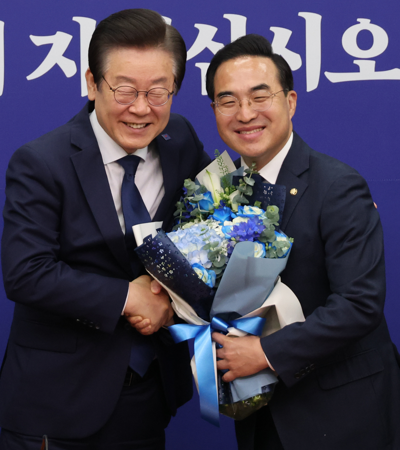 이재명 더불어민주당 대표가 28일 국회에서 당 최고위 전 임기 마지막 날인 박홍근 원내대표에게 꽃다발을 주고 있다. [연합]