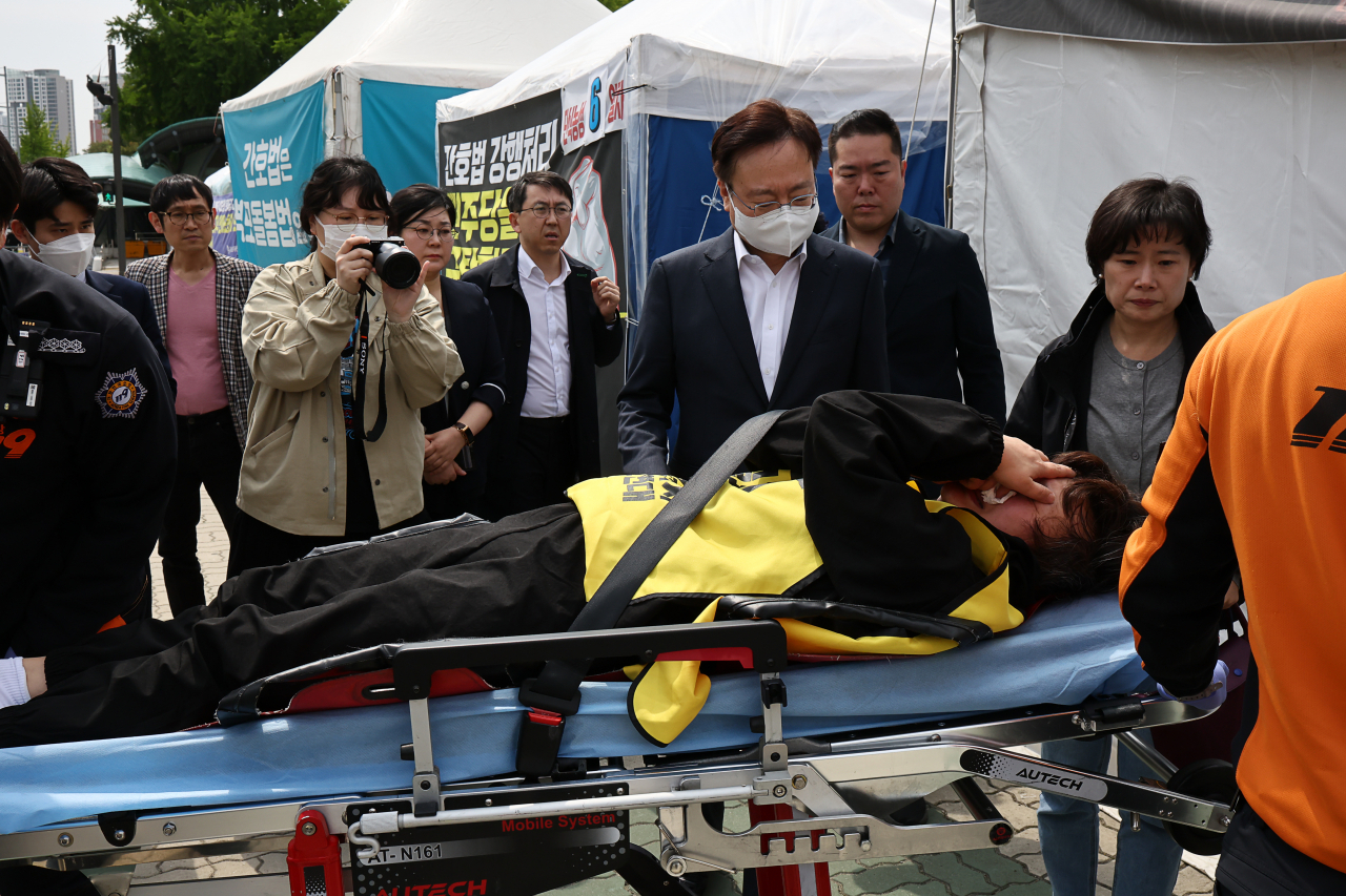 30일 오후 국회 앞 천막 단식 중인 곽지연 대한간호조무사협회장이 병원으로 이송되고 있다. 가운데는 조규홍 보건복지부 장관. [연합]