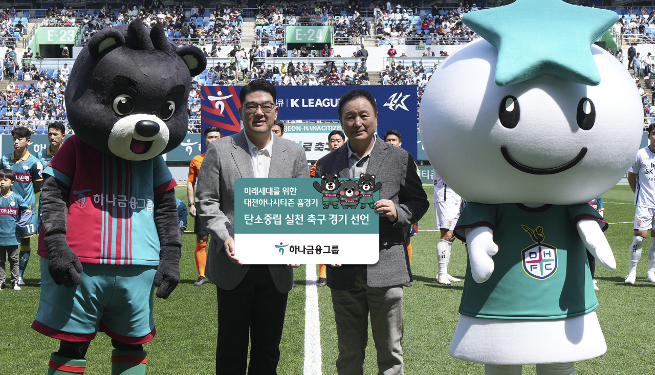 하나금융그룹 ‘대전하나시티즌’이 지난 30일 대전월드컵경기장에서 열린 ‘하나원큐 K리그1’ 홈경기에서 미래 세대를 위해 탄소배출량 제로에 도전하는 탄소중립 실천 축구 경기시행을 선언했다. 이날 경기장을 찾은 이은형(왼쪽) 하나금융그룹 부회장과 허정무 재단법인 하나금융축구단 이사장이 탄소중립 실천 축구 경기를 선언하는 기념 촬영을 하고 있다. [하나금융지주 제공]