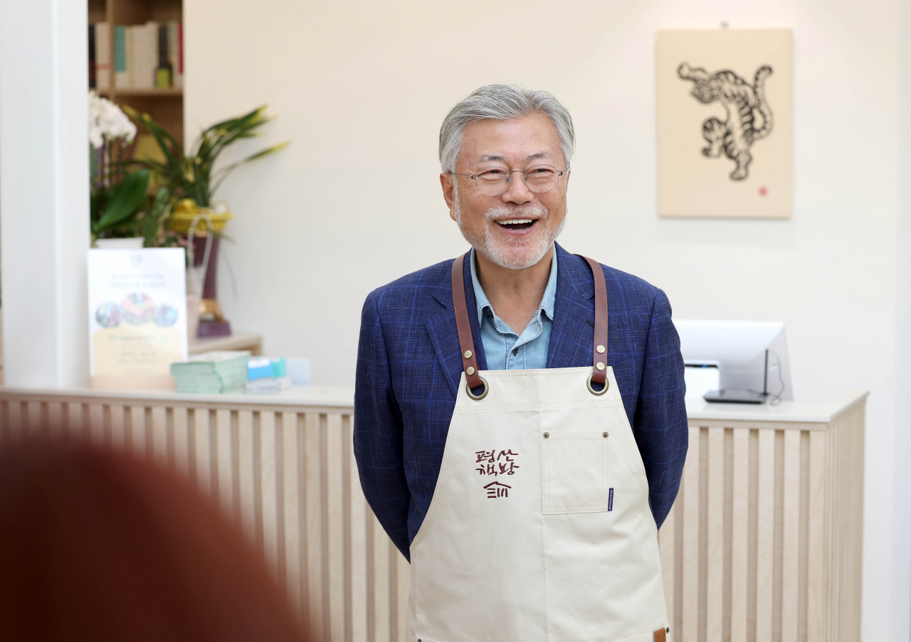 문재인 전 대통령이 26일 오후 경남 양산시 하북면 자신의 책방 '평산책방'에서 앞치마를 착용하며 밝은 표정을 짓고 있다. [연합]