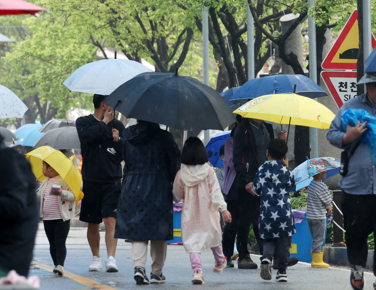 어린이날인 5일 강원 양구군 서천 레포츠공원에서 열린 '2023 양구 곰취축제'에서 우산과 우의 차림의 가족 단위 탐방객들이 궂은 날씨에도 휴일을 즐기고 있다. [연합]