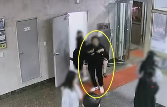 지난달 15일 부산 북구 주상복합건물에서 화재가 발생하자 북부경찰서 김동희 형사(노란 선)가 13층에 살던 거동이 불편한 87세 할머니를 업고 계단으로 내려왔다. 김 형사와 할머니가 1층에 무사히 도착한 모습. [사진=부산경찰청 제공]