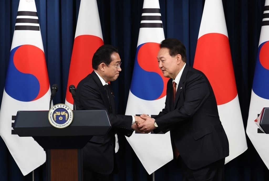 South Korean President Yoon Suk Yeol (right) and Japanese Prime Minister Fumio Kishida shake hands as they hold a joint press conference following their talks at the presidential office in Seoul on Sunday. (Yonhap)