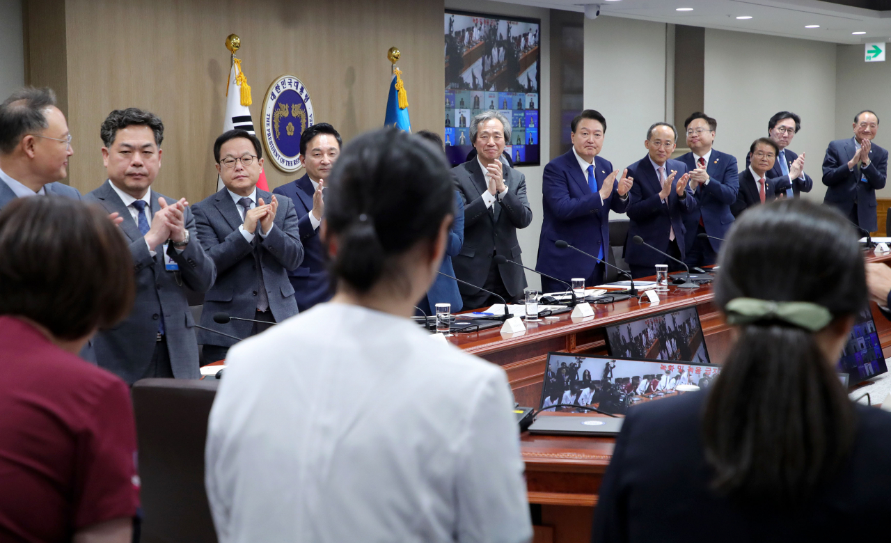 윤석열 대통령과 중대본 위원들이 11일 서울 용산 대통령실 청사에서 열린 코로나19 중앙재난안전대책본부 회의에 앞서 코로나19 방역 최전선에서 활약한 의사, 간호사, 간호조무사 등 보건의료진에게 격려의 박수를 보내고 있다. [연합]
