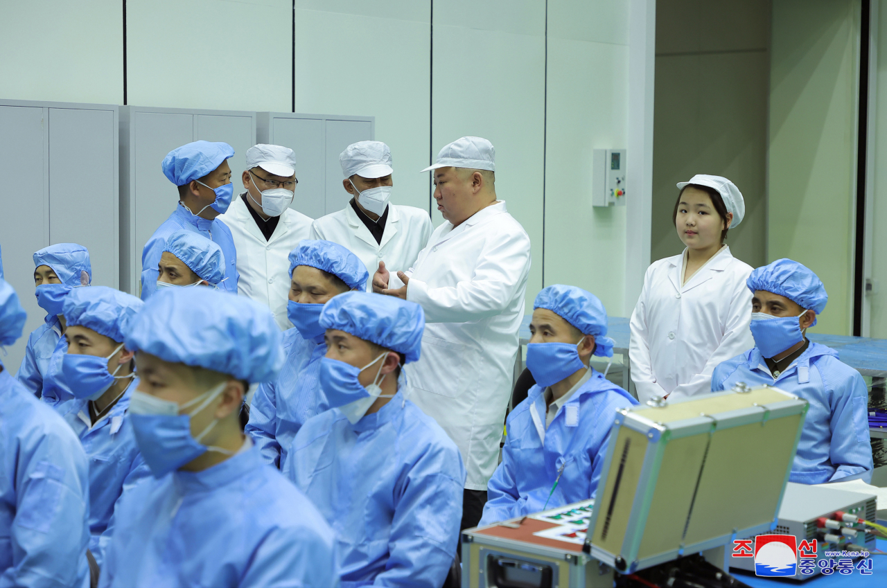 North Korean leader Kim Jong-un (second from right, rear), along with his daughter Ju-ae (far right, rear), talks with members of the Non-permanent Satellite Launch Preparatory Committee in Pyongyang on Tuesday to inspect the country's first military reconnaissance satellite. Kim gave the green light for its "future action plan," Pyongyang's state media said. (KCNA)
