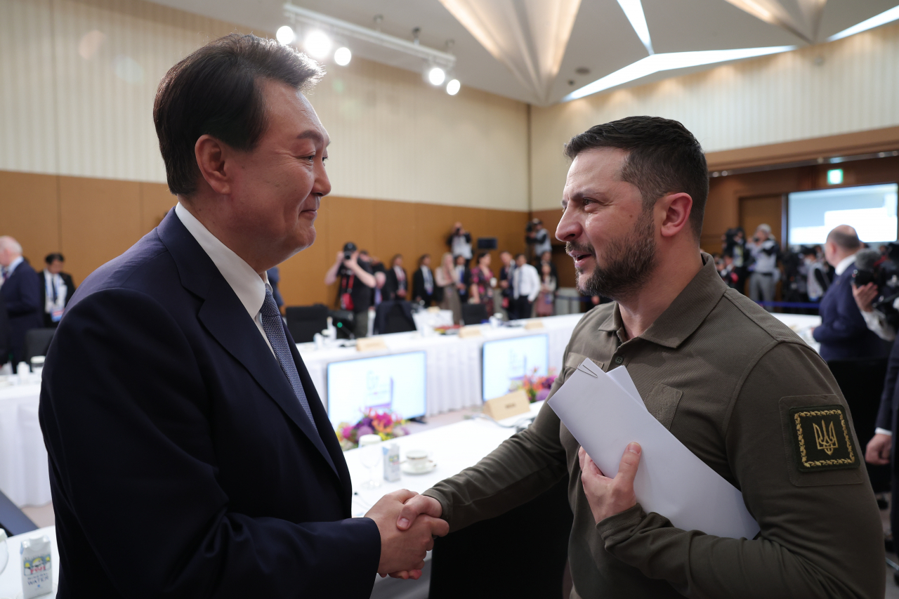 G7 정상회의 참관국 자격으로 일본을 방문 중인 윤석열 대통령과 G7 정상회의에 전격적으로 참석한 볼로디미르 젤렌스키 우크라이나 대통령이 21일 히로시마 그랜드프린스호텔에서 열린 G7 정상회의 확대세션에서 만나 악수하고 있다. [연합]