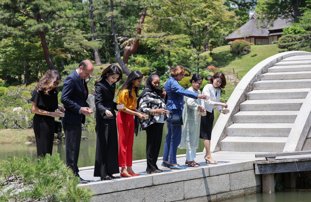 윤석열 대통령과 함께 일본을 방문 중인 김건희 여사가 21일 히로시마의 대표적 정원인 슈케이엔에서 열린 G7 정상회의 공식 배우자 프로그램에 참석해 다리 위에서 잉어에게 먹이를 주고 있다. [연합]