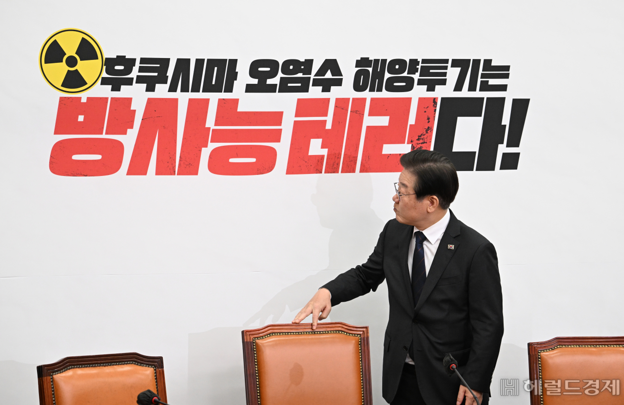 이재명 더불어민주당 당대표가 22일 서울 영등포구 여의도 국회의사당 본청에서 열린 더불어민주당 최고위원회의에 참석한 가운데 착석 전 뒷배경판 문구를 살펴보고 있다. 임세준 기자