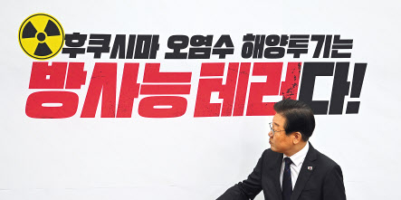 이재명 더불어민주당 대표가 22일 국회에서 열린 최고위원회의에 입장하며 뒷배경판 문구를 보고 있다. 임세준 기자