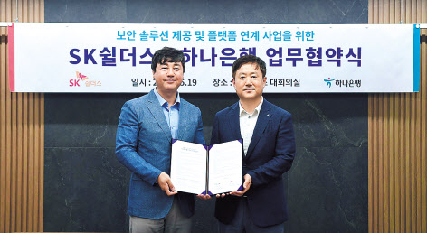 김윤호(왼쪽) SK쉴더스 성장추진실장과 이동현 하나은행 기업사업본부 본부장이 사진 촬영을 하고 있다. [SK쉴더스 제공]