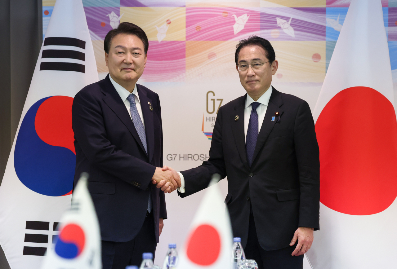 South Korean President Yoon Suk Yeol (left) and Japanese Prime Minister Fumio Kishida shake hands during a summit in Hiroshima, Japan last Sunday. (Yonhap)