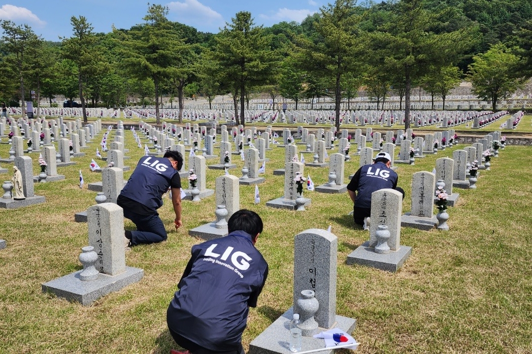 국립서울현충원 자매결연 묘역 봉사활동에 나선 LIG넥스원 직원들이 잡초제거와 비석 닦기 등 주변 정화활동을 벌이고 있다. [LIG넥스원 제공]