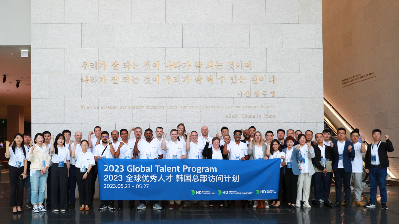 HD현대 건설기계 3개사 글로벌 인재들이 지난 23일 판교 글로벌R&D(연구개발)센터를 방문해 정주영 창업자의 어록이 새겨진 그레이트월에서 기념촬영을 하고 있다. [HD현대사이트솔루션 제공]