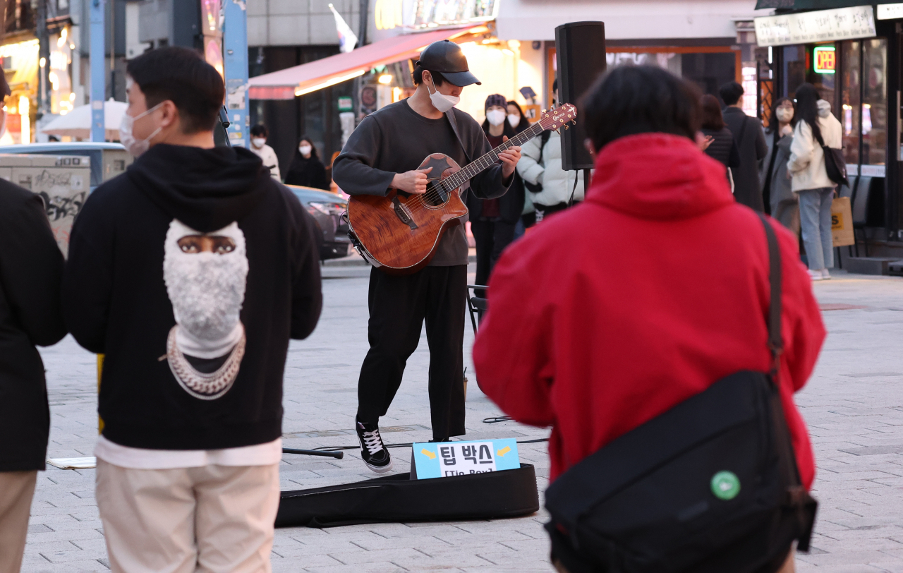 코로나19 오미크론 변이로 인한 신규 확진과 세자릿수 사망자 발생이 지속되고 있지만 사회적 거리두기가 완화되면서 코로나19 이전의 삶으로 돌아가기 위한 발걸음이 시작되고 있다. 31일 오후 서울 마포구 홍대앞 젊음의 거리에서 한 예술가가 길거리 공연을 하고 있다. 이날 이 거리에서 공연을 한 예술가는 많지 않았지만 팬데믹 이후 금지됐던 '버스킹'이 허용되면서 시민들은 공연을 보며 저녁 시간을 즐겼다. 팬데믹 이후 금지됐던 홍대 앞 '버스킹'은 이날부터 예약을 받기 시작해 4월 공연 예약은 모두 찼다. 평일도 오후 6시부터 8시까지 주요 시간대는 마감됐고, '불금'에도 노래와 댄스 등 다양한 장르로 '버스킹'을 하려는 사람들이 줄을 섰다. 토요일은 정오부터 전 시간대가 마감이다. 연합뉴스