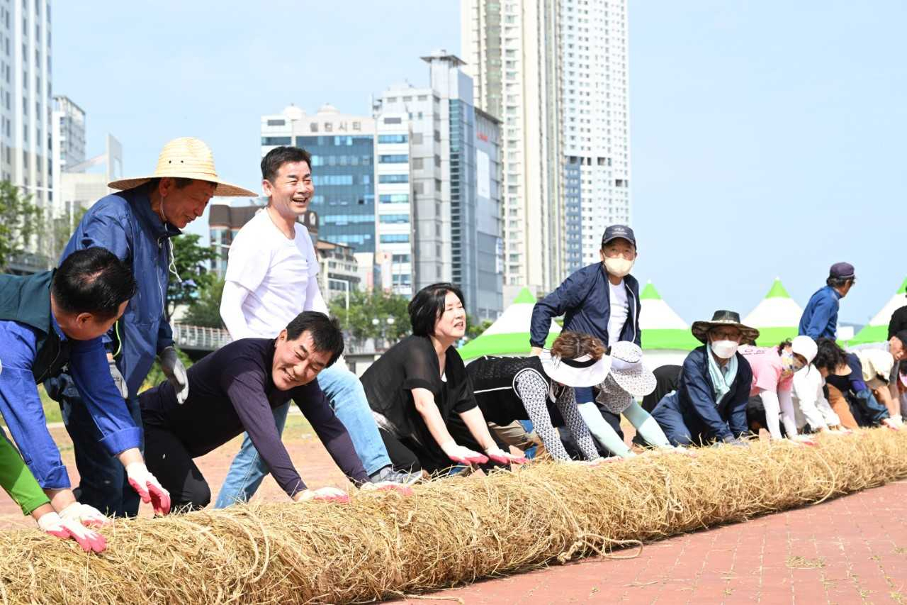 27일 울산 태화강 체육공원에서 김영길 울산 중구청장과 태화강마두희축제추진위원회 관계자, 마두희보존회 회원, 지역주민 등이 태화강마두희축제 마두희 큰줄당기기에 쓰일 마두희 본 줄(몸통 줄) 제작 행사에 참여하고 있다. [사진=울산 중구]