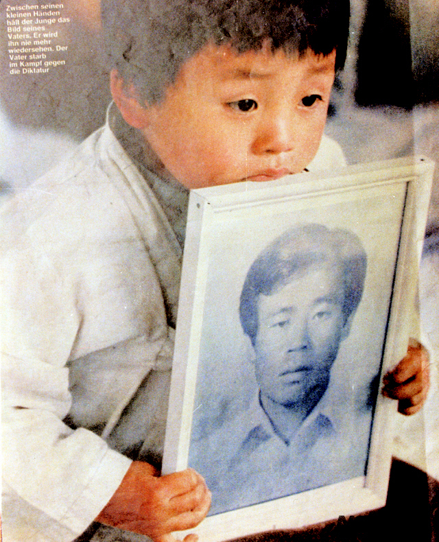 2019년 5월 18일 5·18민주화운동 39주년 기념식이 열린 가운데 문재인 대통령이 1980년 5월21일 광주 금남로에서 계엄군 총에 맞아 숨진 조사천 씨(당시 34세)의 묘를 찾아 참배했다. 사진은 아들 조천호 씨(당시 5세)가 아버지의 영정사진을 들고 있는 모습[5·18기념재단 제공]