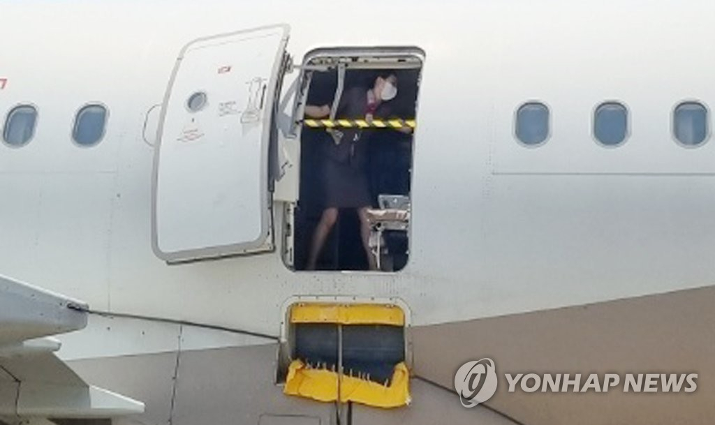 지난 5월 26일 오후 제주공항에서 출발해 대구공항에 비상구 출입문이 열린 채 착륙한 아시아나항공기에서 한 승무원이 문에 안전바를 설치한 뒤 두 팔을 벌려 막고 있다. [대구국제공항 관계자 제공]