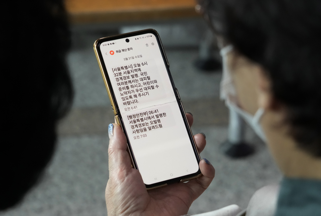 지난 31일 한 여성이 서울의 서울역(기차역)에서 서울 시민들에게 전송된 긴급 대피 경고 문자 메시지를 들여다보고 있다.[AP]
