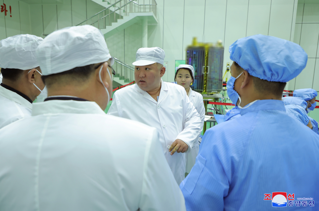 North Korean leader Kim Jong-un (center) is accompanied by his daughter Ju-ae as he talks with members of the Non-permanent Satellite Launch Preparatory Committee in Pyongyang on May 16 to inspect the country's first military reconnaissance satellite, in this photo released by the North's official Korean Central News Agency. (Yonhap)