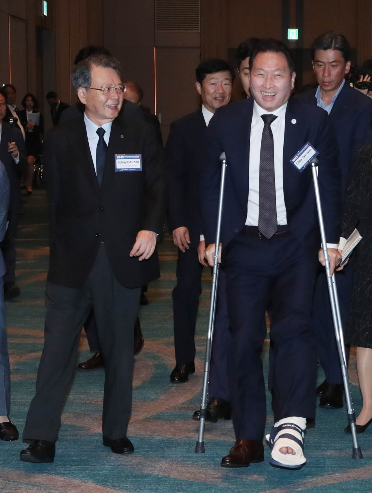 테니스를 치다 발목 부상을 당한 최태원(오른쪽) 대한상의 회장이 고바야시 켄(왼쪽) 일본상의 회장과 한일상공회의소회장단회의장으로 목발을 한 채 입장하고 있다. [대한상의 제공]